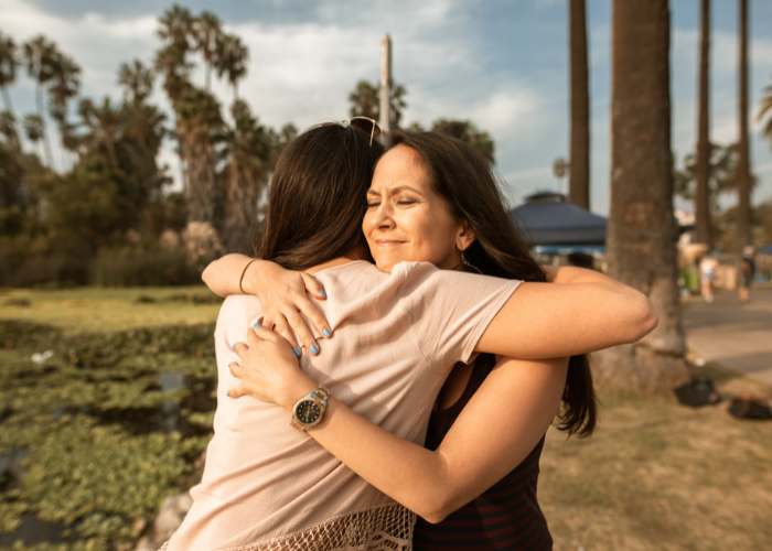 Dos mujeres abrazándose con cariño durante un círculo de madres, símbolo de apoyo, confianza y unión femenina