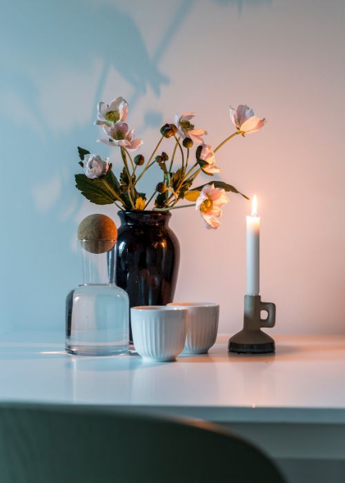 Rincón preparado para un círculo de madres, con jarrón de flores, vela encendida y tazas de té que transmiten calma y unión
