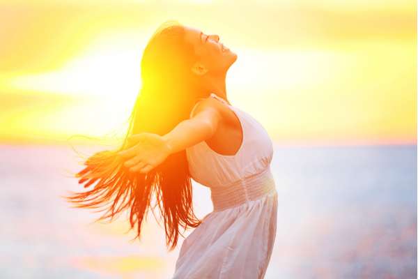 Mujer disfrutando del atardecer junto al mar, símbolo de libertad, energía positiva y conexión en un círculo de mujeres
