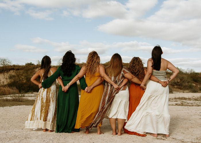 Grupo de mujeres unidas de espaldas en un círculo de hermandad y apoyo femenino