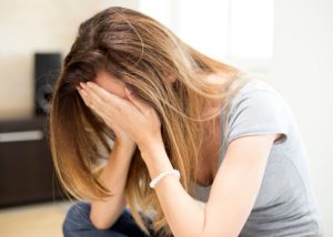 Madre con las manos en la cara que se siente culpable tras perder los nervios con su hijo